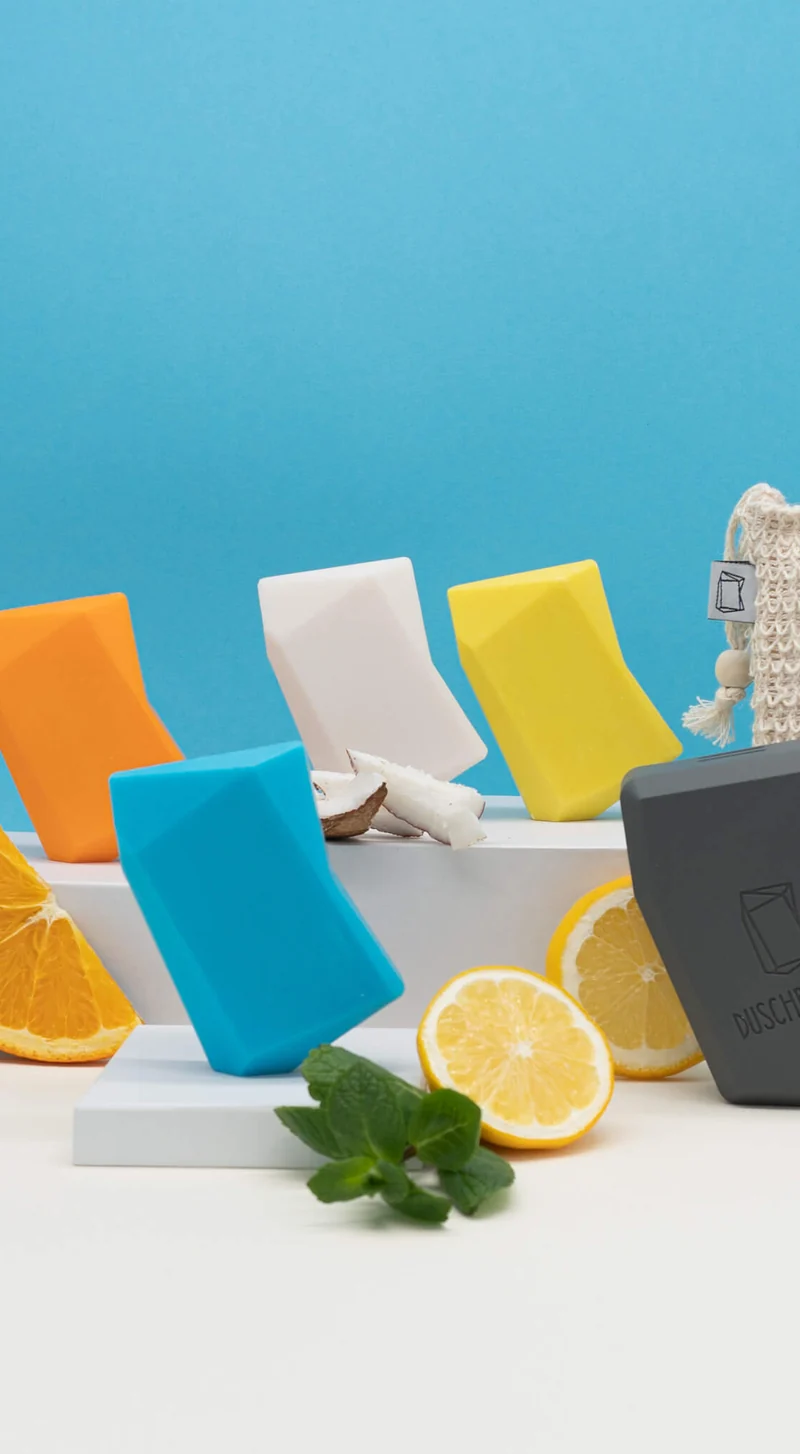 Bunte Duschbrocken mit Zitrusfrüchten vor blauer Wand